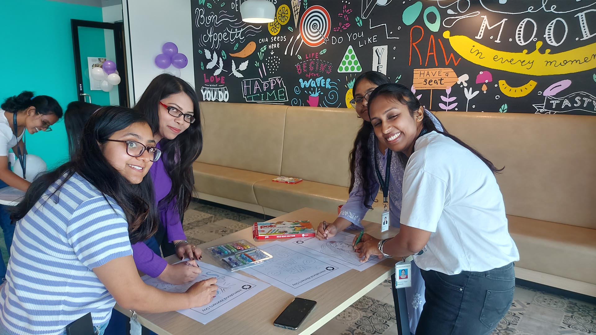 Four girls collaborate on a project together at a table, focused and engaged in their work.