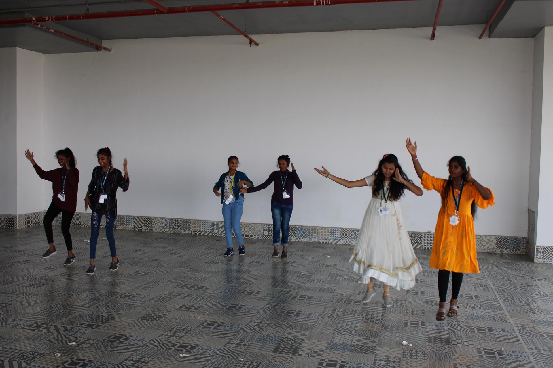 A group of women joyfully dancing together in a spacious, empty room