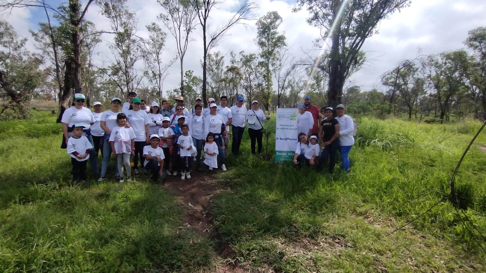 Crowd of people posing for a picture standing in a green field