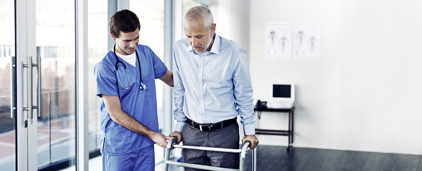 Male nurse helping handicapped elderly man walk