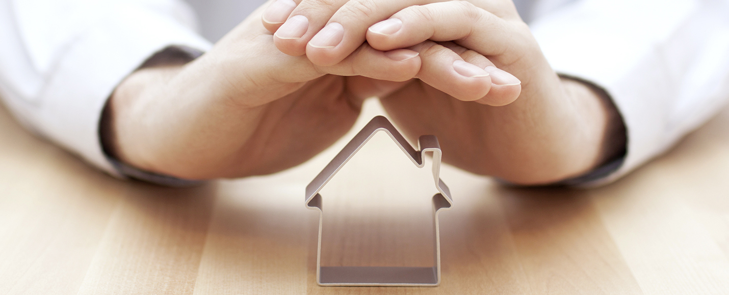 Hands folded over roof of miniature house