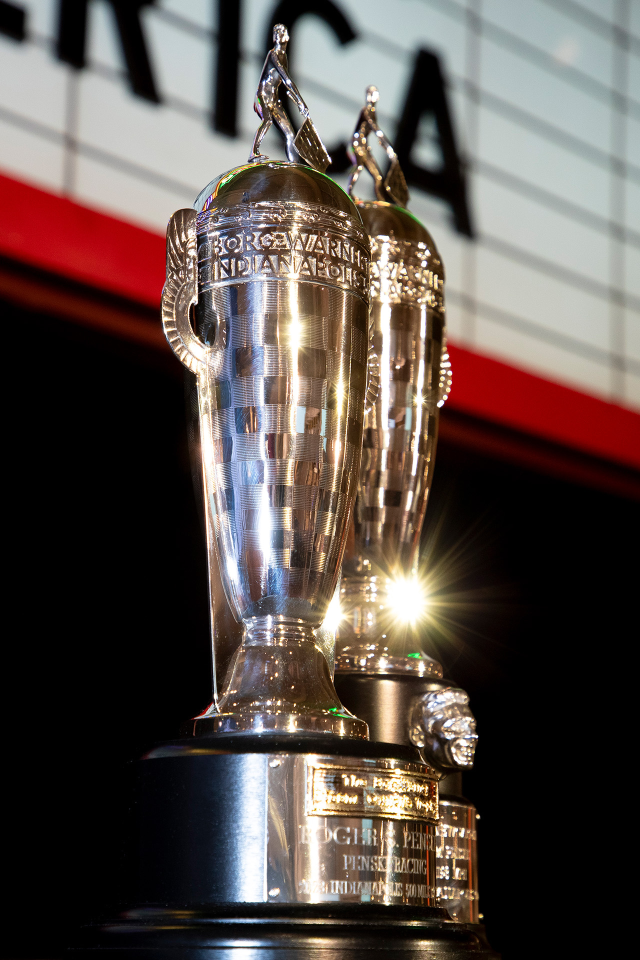 Two silver trophies on table in front of marquee sign