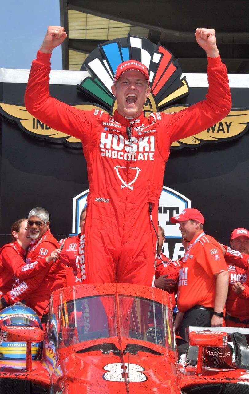 a person in a red driver uniform with his arms raised