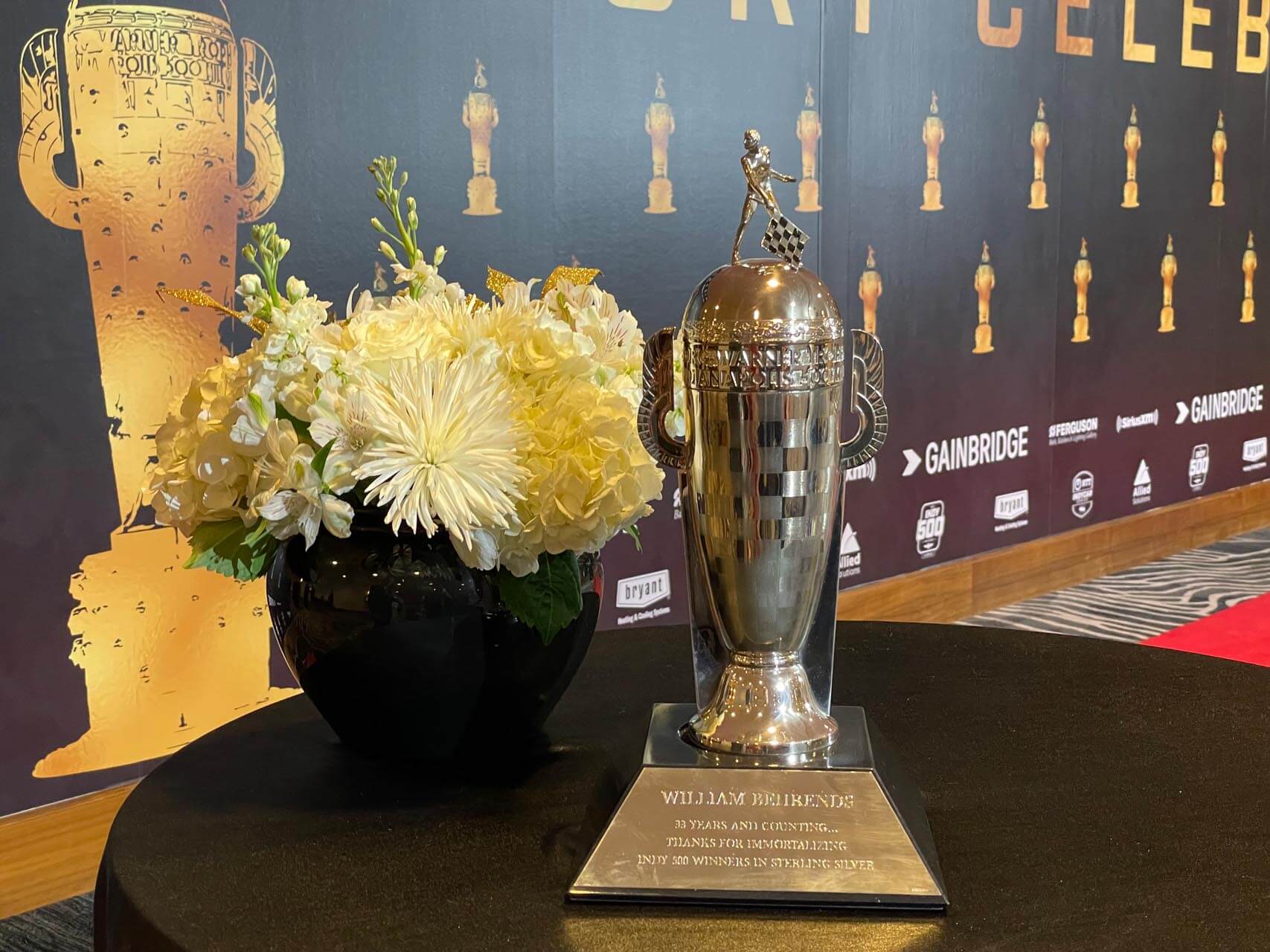 Silver trophy and white flowers on table