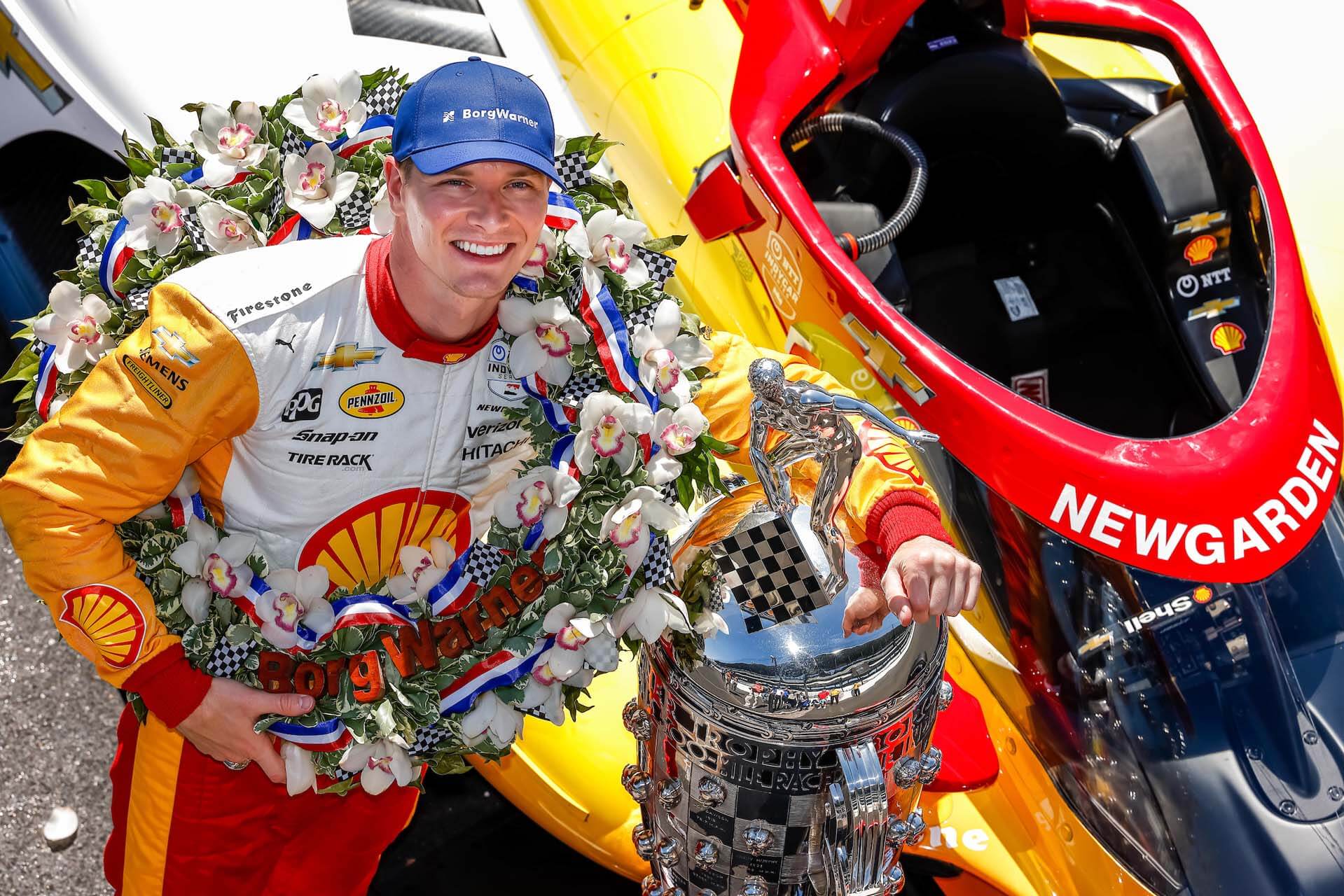 Man poses with race car and silver trophy