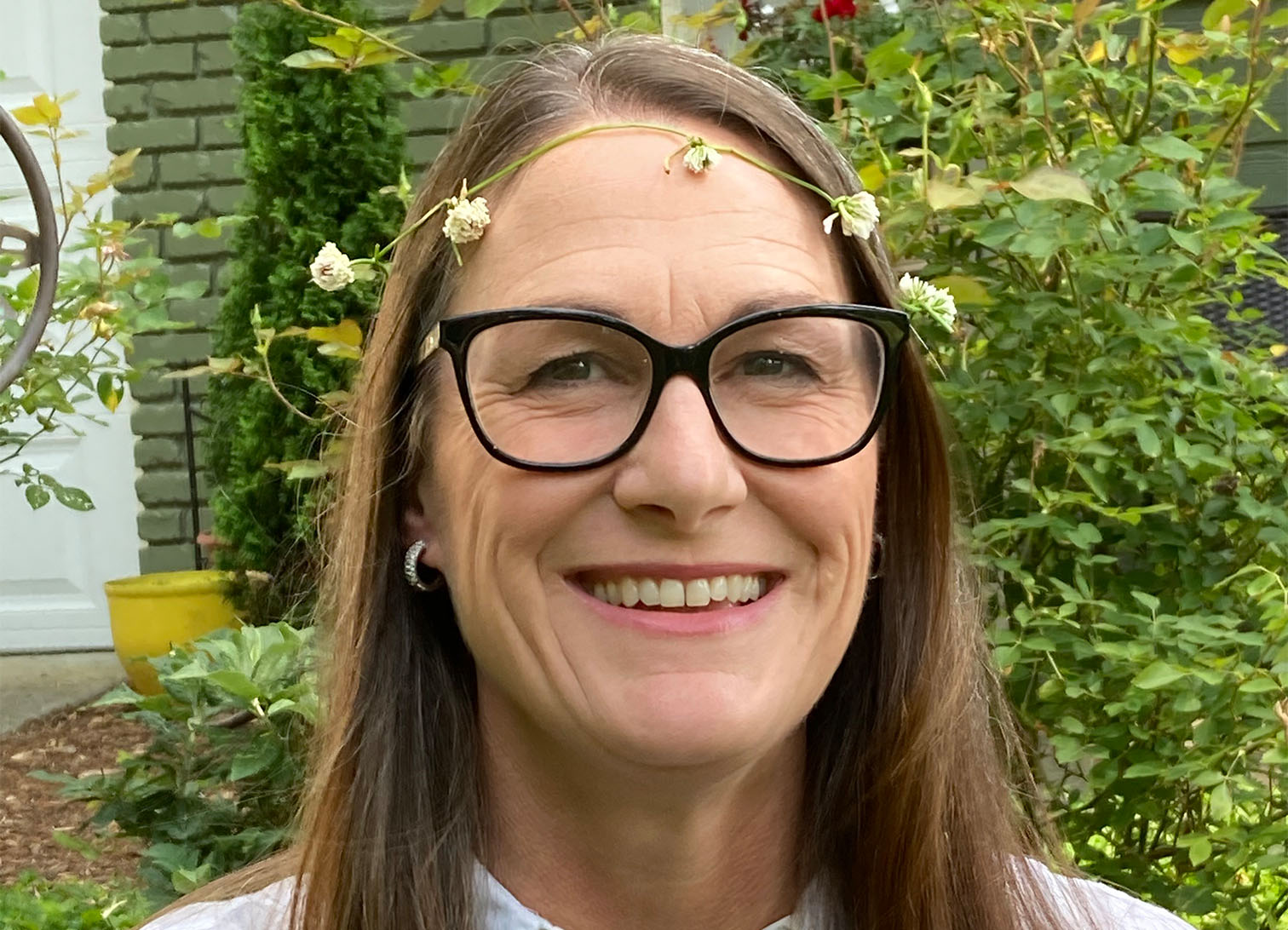 Headshot of women outdoors surrounded by greenery with white blouse