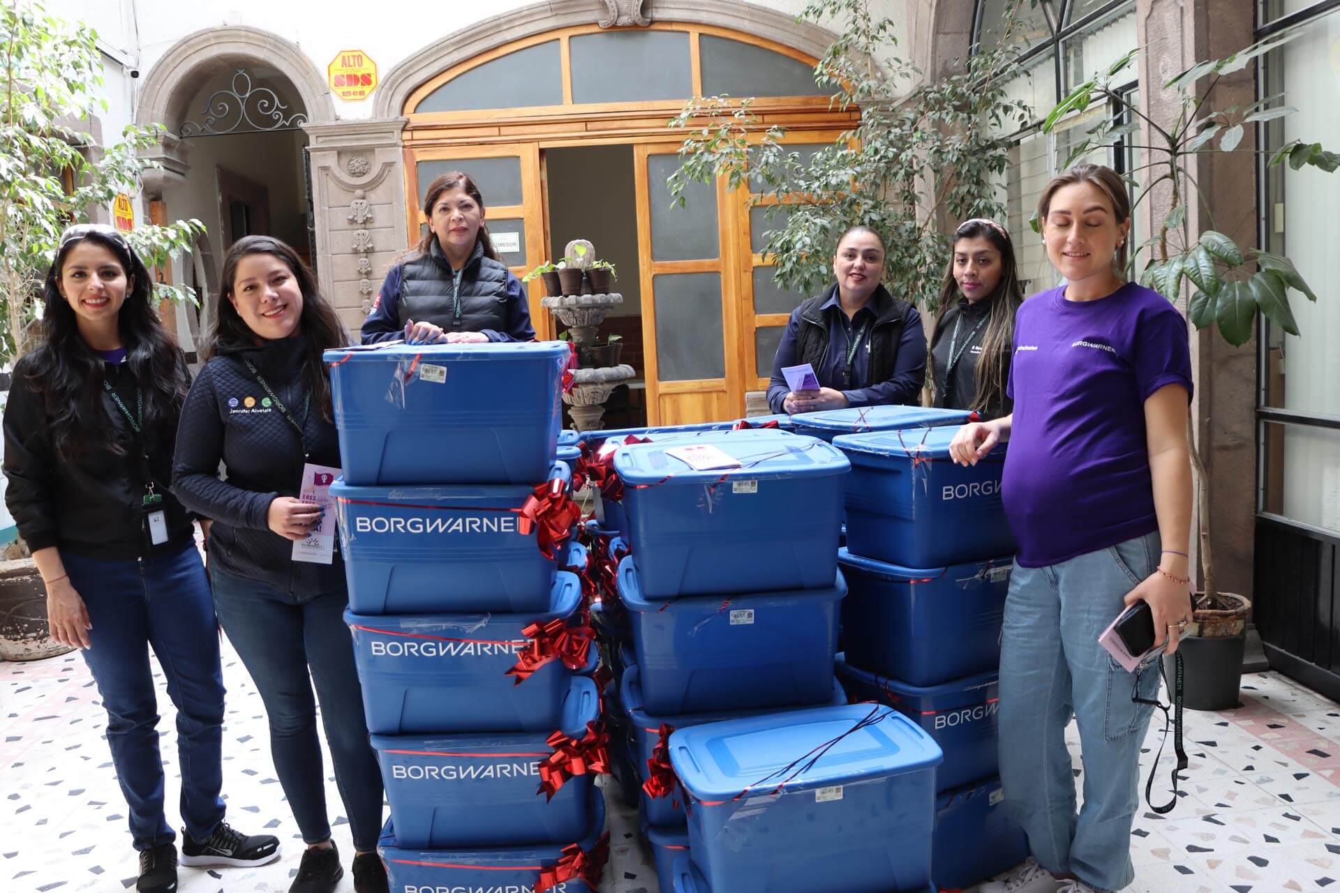 a group of women standing next to a stack of blue containers